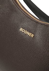 Brązowa, teksturowana skórzana torebka z złotym logo "BOGNER", z metalowym zamkiem błyskawicznym i gładkim czarnym uchwytem.