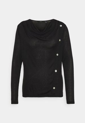 Haut noir à manches longues avec encolure drapée et cinq boutons blancs verticaux le long de l'épaule droite et de la couture latérale.