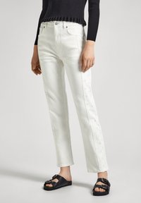 Beli denim jeans z vezenjem na straneh, ravnega kroja, visokega pasu, v kombinaciji s črnimi natikači z zaponko.