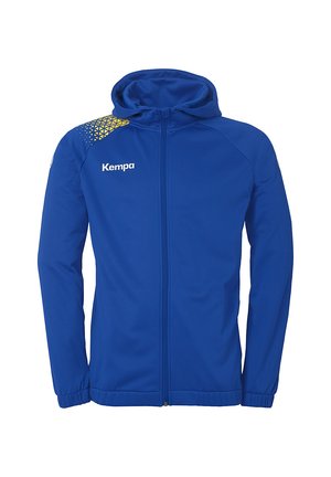 Blå sportsjakke med lynlås fortigt, hætte og elastiske manchetter. Har et geometrisk gult design på venstre skulder. "Kempa" logo på brystet.