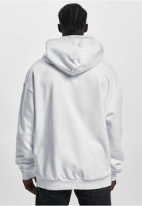 Sweat à capuche blanc avec poche kangourou, capuche à cordon ajustable et poignets côtelés. Confectionné en tissu doux avec une coupe décontractée.