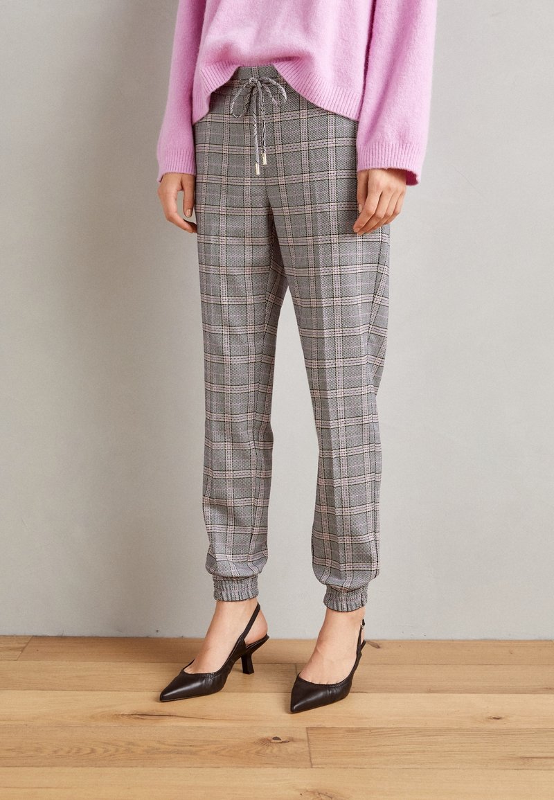 Gray plaid jogger pants with elastic cuffs and drawstring waist, paired with black pointed-toe slingback heels.