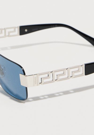 Γυαλιά ηλίου με μπλε φακούς, μαύρους βραχίονες και ασημένιο γεωμετρικό σχέδιο ελληνικού κλειδιού στους βραχίονες, με διακριτική χάραξη του λογότυπου.