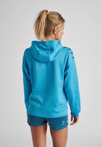 Felpa blu con cappuccio, maniche lunghe e tessuto texturizzato, abbinata a pantaloni corti coordinati con dettagli del logo.
