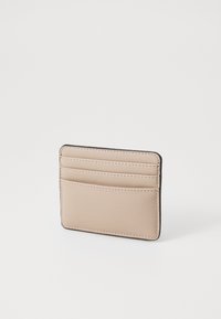 Beige leather cardholder with four slots, contrasting stitching, and a slim rectangular shape. Smooth texture and minimal design.