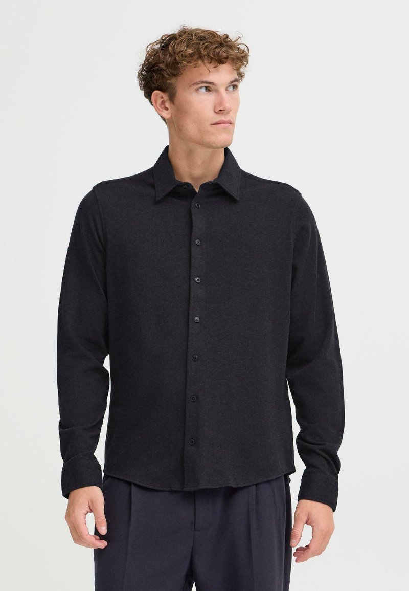 Camicia nera a maniche lunghe realizzata in materiale morbido, con chiusura a bottoni, colletto classico e vestibilità rilassata con dettagli di cucitura sottili.