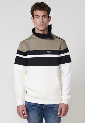Suéter en oliva, negro, blanco y crema con un cuello alto, cremallera y bolsillo frontal; presenta rayas horizontales bold y logo.