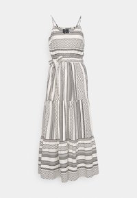 Robe maxi sans manches à motif blanc et noir avec des bretelles spaghetti et une ceinture nouée à la taille, présentant des motifs de rayures verticales et géométriques.