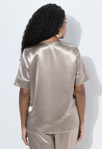 Satin, kurzärmliges Top in metallic taupe. Verfügt über eine entspannte Passform mit einer glatten Textur und einem schlichten Rundhalsausschnitt.