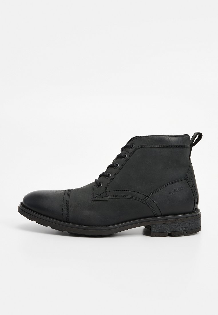 Botín negro de cuero con cordones delanteros, puntera redondeada, detalles de costura y suela de goma texturizada, con una lengüeta para tirar en la parte trasera.