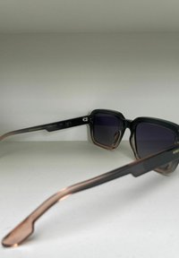 Svart och brun gradient solglasögon med rektangulär ram, tonade linser och en elegant design. Har metallaccenter på bågarna.