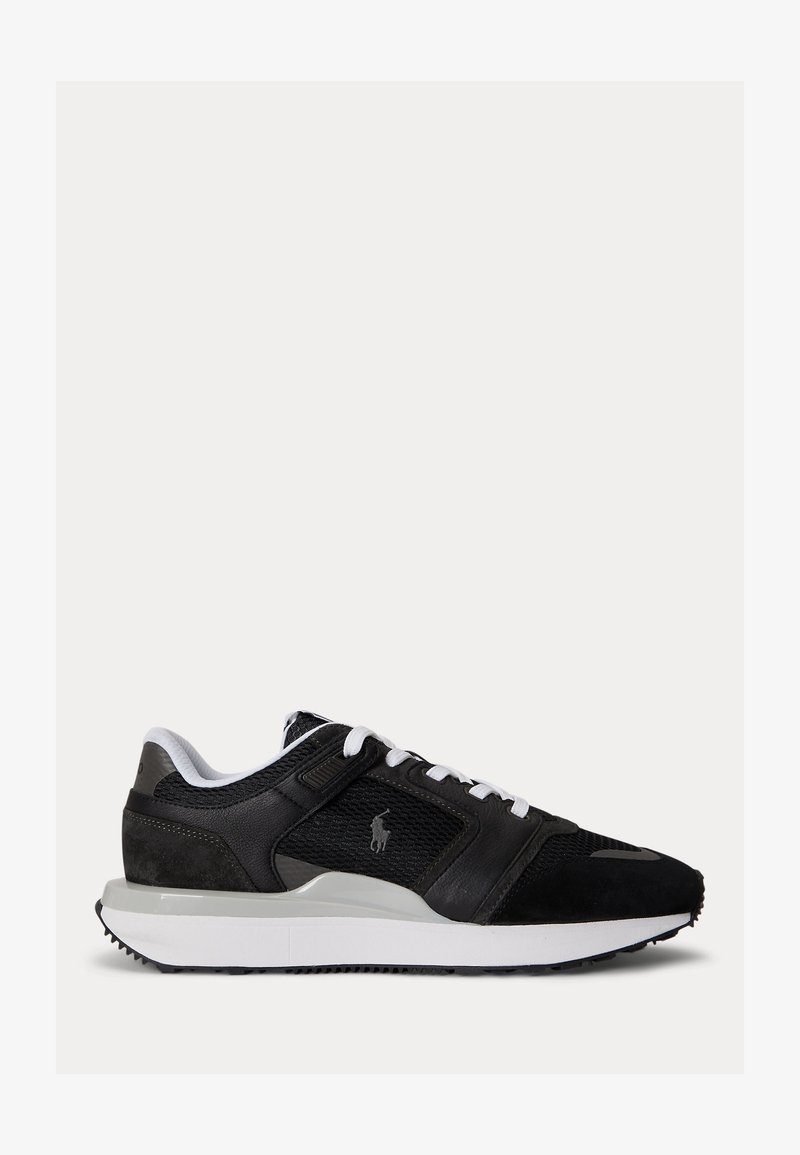 Ασπρόμαυρο χαμηλό αθλητικό παπούτσι με επάνω μέρος από δίχτυ και δέρμα, λευκά κορδόνια, επενδεδυμένη σόλα και κεντημένο λογότυπο στην πλευρική επιφάνεια.