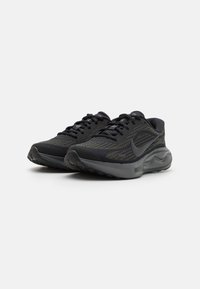 Pari mustia ja tummanharmaita Nike-juoksukenkiä, joissa on nauhakiinnitys ja kuvioitu verkkokangas, esitetty valkoista taustaa vasten.