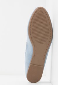 Chaussure en daim bleu clair montrant la semelle marron texturée avec le numéro de taille sept embossé près du talon.
