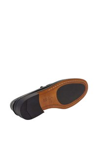 Crna kožna potplat cipela s smešnim naglascima, s teksturiranom površinom, kontrastnim gumenim potpeticom i šivenim detaljima duž ivice.