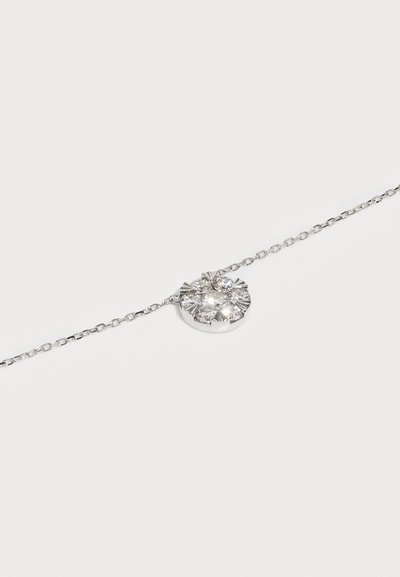 Silberarmband mit einem runden, strukturierten Anhänger, der drei klare, funkelnde Steine enthält. Die Kette hat kleine Glieder, die das zarte Design unterstreichen.