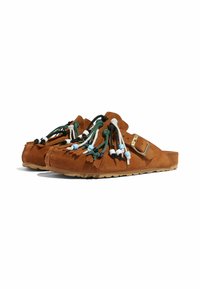 Braune Wildleder-Slipper mit mehrfarbigen Quasten und Perlenverzierungen; runde Zehenform, flache Sohle mit strukturierter Griffoberfläche und verstellbarem Riemen.