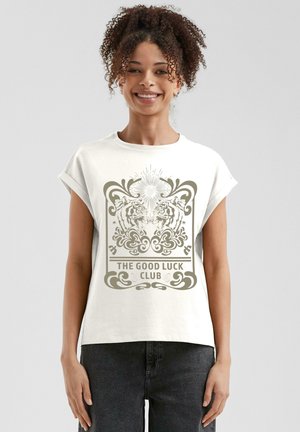 White short-sleeve T-shirt featuring a decorative graphic in beige, depicting two tigers and ornate swirls, with text reading "THE GOOD LUCK CLUB."