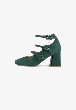 Chaussure à talons hauts en daim turquoise avec un bout pointu, trois sangles ornées de pierres vertes, et un talon carré avec un accent noir.