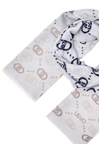 Bufanda blanca con un patrón repetido de logos entrelazados en beige y azul marino, con detalles de flecos a lo largo de los bordes.