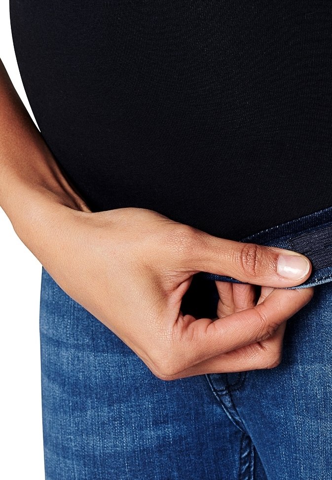 Tummansiniset farkut, joissa on venyvä vyötärö, näyttävät sileältä. Kädessä pidetään vyötäröstä, mikä osoittaa kankaan joustavuutta.