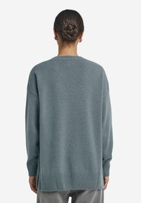 Helles blaues, oversized Sweatshirt mit langen Ärmeln, geripptem Saum und seitlichen Schlitzen. Weicher Stoff, lässiges Design und runder Ausschnitt.
