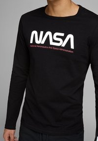 Camiseta de manga larga negra que presenta un destacado logo blanco de "NASA" y el texto rojo "Administración Nacional de Aeronáutica y del Espacio."