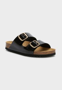 Svart patentläder slidesandal med två justerbara spännen, korkunderlag och texturerad gummisula. Har en slät yta och minimalistisk design.
