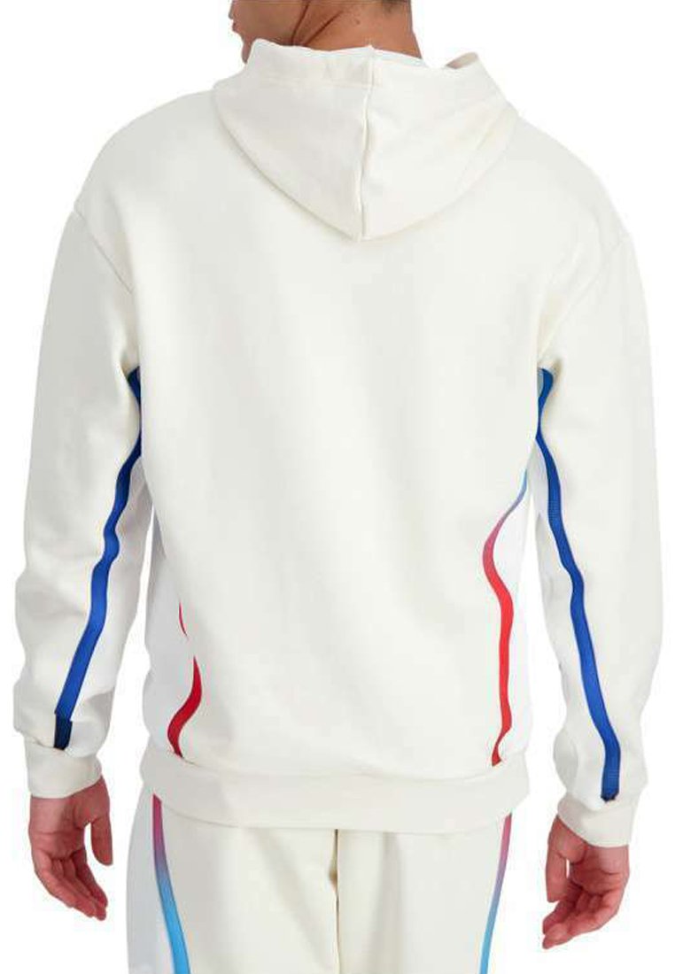 Hombre vestido con una sudadera blanca y pantalones a juego con franjas laterales azules y rojas, visto desde atrás sobre un fondo liso.