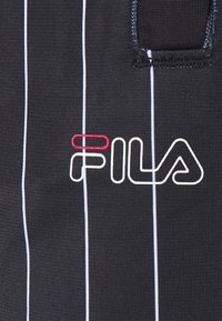 Schwarzer Stoff mit vertikalen weißen und hellblauen Streifen, vorne mit einem rot-weißen bestickten "FILA"-Logo.