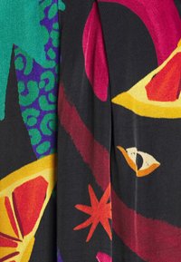 Tissu aux couleurs vives avec des tranches de fruits abstraites, des formes d'étoiles et des motifs léopard dans des teintes de rouge, jaune, violet, vert et noir.