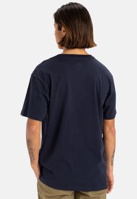 Camiseta de algodón azul marino con mangas cortas y cuello redondo. Textura suave, corte relajado y mínimos detalles de costura en los dobladillos.