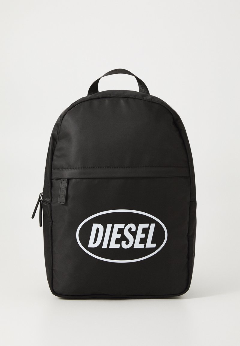 Juodas nailono kuprinės forma su apvaliais kraštais, ant priekinės pusės didelis baltas "DIESEL" logotipas, viršuje esantis rankenėlis ir priekinė kišenė su užtrauktuku.