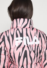 Giacca a vento rosa con strisce zebrate nere, dotata di un alto colletto e del logo FILA bianco in evidenza sul retro. Tessuto trapuntato e strutturato.