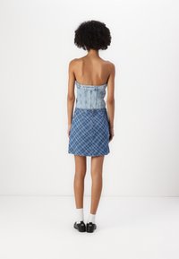 Denim topp med en strapless design och ljus tvätt, tillsammans med en rutig denim mini kjol i mörkare blå nyanser, slät textur, avslappnad stil.