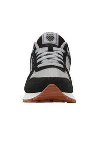 Czarne i szare buty sportowe z zamszową i siateczkową cholewką, płaskimi sznurowadłami, gumową podeszwą oraz logo na języku. Okrągły kształt noska.