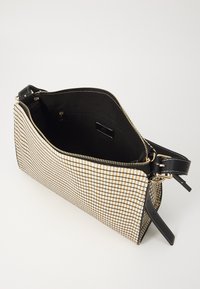 Borsa a mano check in beige e nero con forma strutturata, chiusura con cerniera, spallacci in pelle nera e interno liscio con tasca a zip.