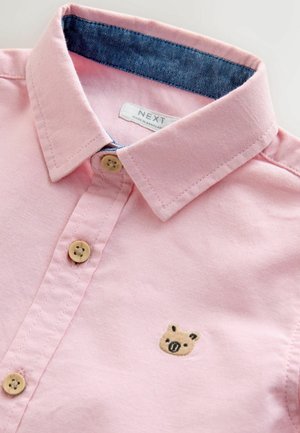 Hellrosa Baumwollhemd mit Kragen, das einen denimgefütterten Halsausschnitt und eine Schweinstickerei in der Nähe der Knöpfe aufweist. Die Knöpfe sind hellbraun.