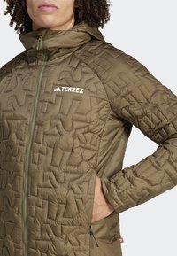Olive green insulated jacket with a textured geometric pattern, full zip, hood, and zippered pockets. Includes "TERREX" logo on chest.