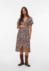 Vestido tipo wrap en un burdeos profundo con un patrón abstracto en blanco. Escote en V, mangas con vuelo, a la altura de la rodilla con una abertura lateral. Botas marrones.