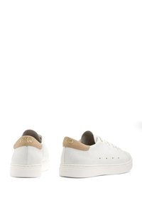 Weiße Leder-Sneaker mit strukturiertem Finish, beigen Fersenelementen und goldenem Logo auf der Rückseite. Mit flachen Schnürsenkeln und einer Gummisohle ausgestattet.