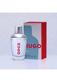 Klar glasparfumflaske med sølvkapsel mærket "HUGO ICED" ved siden af en rød, grå og blå æske med samme mærke.