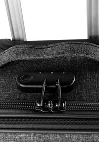 Equipaje de tela negra con superficie texturizada, doble cremallera y un mecanismo de cierre negro en la parte superior para mayor seguridad.