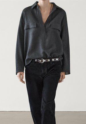 Gray, long-sleeve shirt with a collared neck, featuring a partial button placket and two chest pockets, paired with black denim pants and a brown belt.