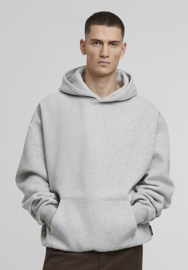 Grauer Hoodie aus weicher Baumwolle, mit großer Kapuze, vorderer Kängurutasche, lockerer Passform und gerippten Bündchen. Einfaches, unauffälliges Design.