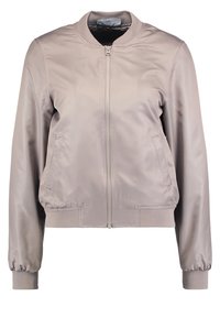 Chaqueta bomber de un tono beige claro, fabricada en un material suave, con cremallera frontal, bolsillos laterales, puños acanalados y un cuello redondo.
