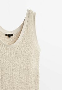 Débardeur en tricot beige sans manches avec des bords côtelés et un col arrondi, posé à plat sur un fond blanc.