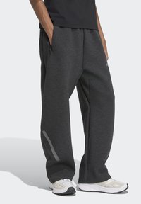 Sivé nohavice so širokými nohavicami a elastickým pásom, ktoré majú bočné vrecká a reflexné akcenty na dolných nohách.