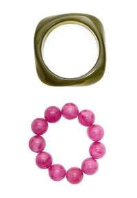 Anello rettangolare verde oliva sopra un braccialetto di perle rosa con sfere lisce e lucide. Entri gli accessori presentano colori solidi e design semplici.