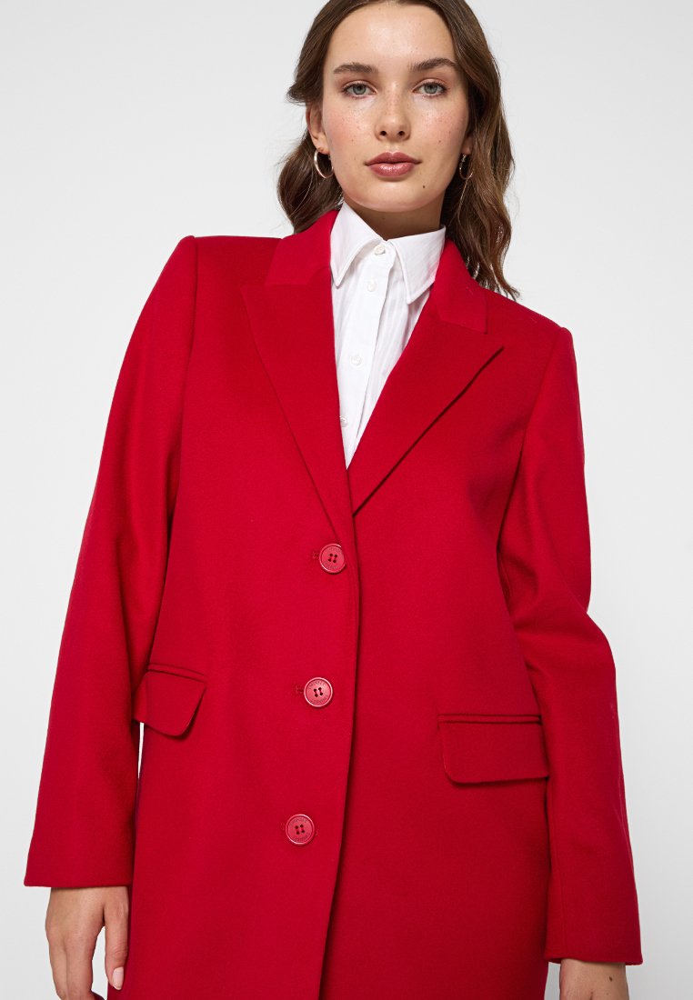 Cappotto rosso in misto lana con colletti a punta, due tasche frontali e due grandi bottoni. Presenta una vestibilità su misura e una texture liscia.